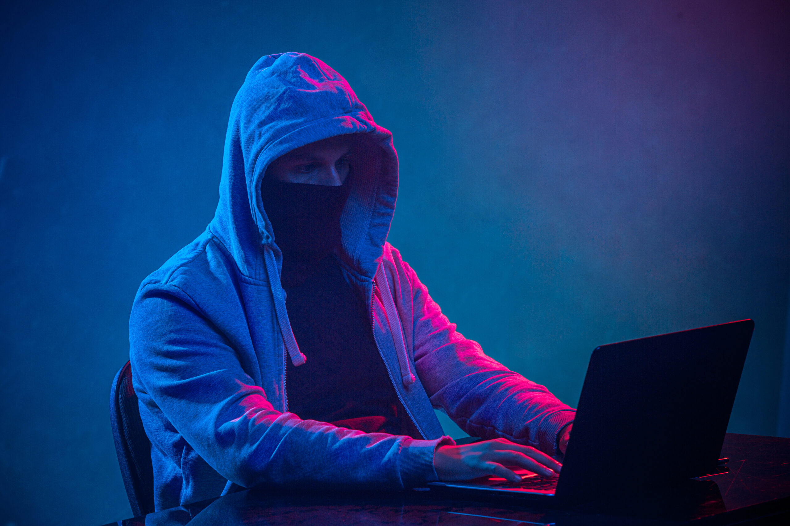 Hooded man on a laptop attempts to carry out a data breach.